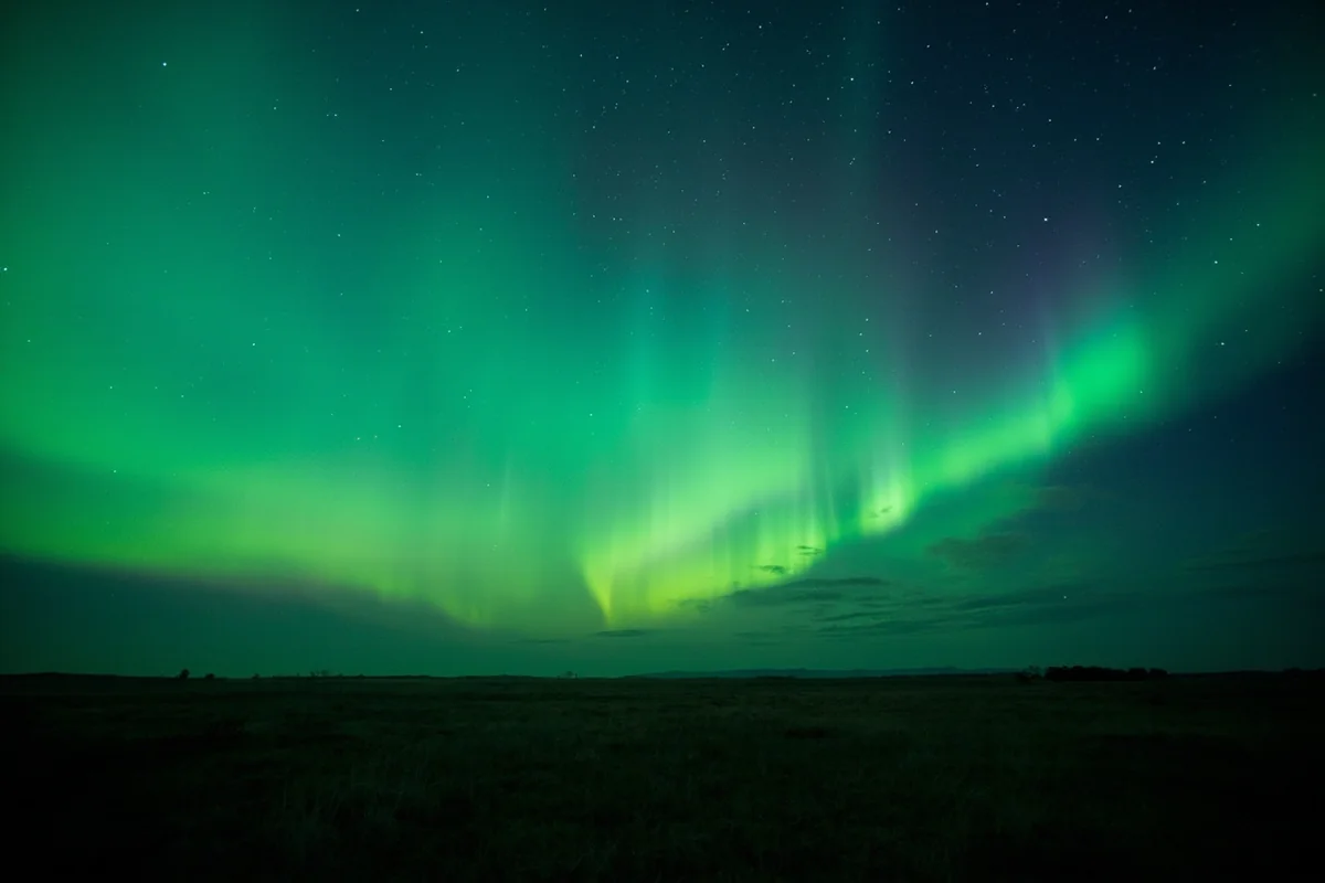 Wide panoramic view of Montana prairie at night with Northern Lights stretching across the entire horizon