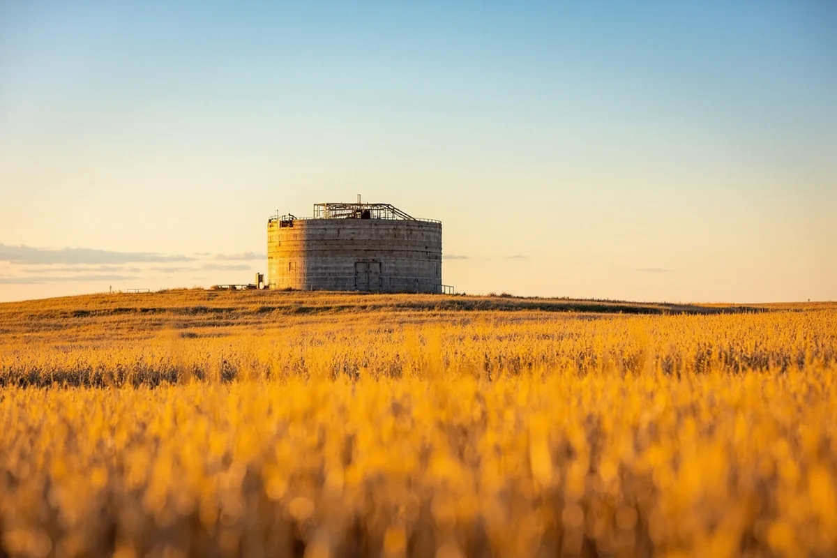 Wide shot of a decommissioned missile silo site surrounded by golden wheat fields near Great Falls, Montana