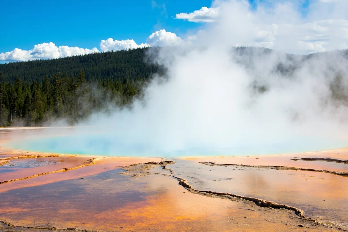 Wide shot of Gigantic Warm Spring main pool with steam rising against mountain backdrop