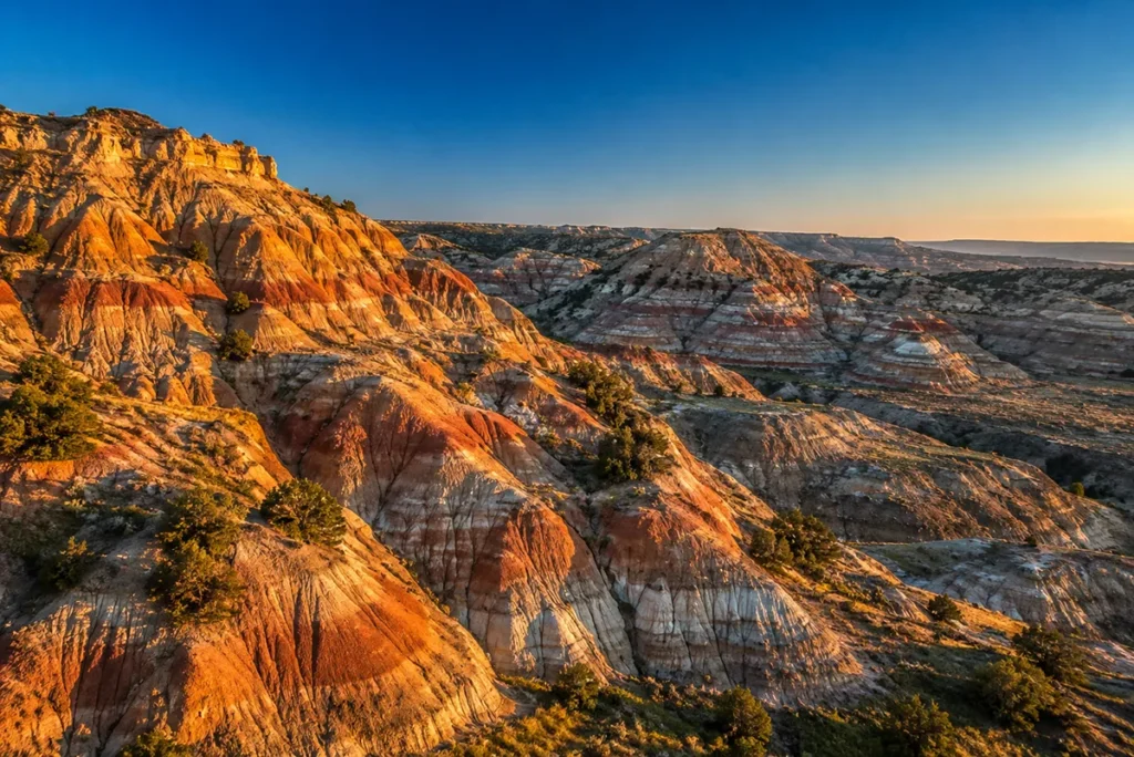Eroded red and tan badland formations of Makoshika State Park glowing at sunrise in southeastern Montana