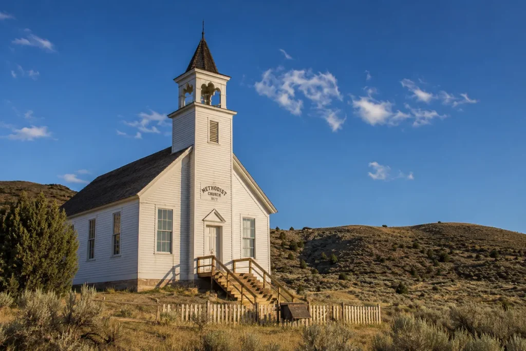 The Methodist Church at Bannack State Park in Montana, a wooden 1877 structure with its steeple intact, standing against a clear blue sky