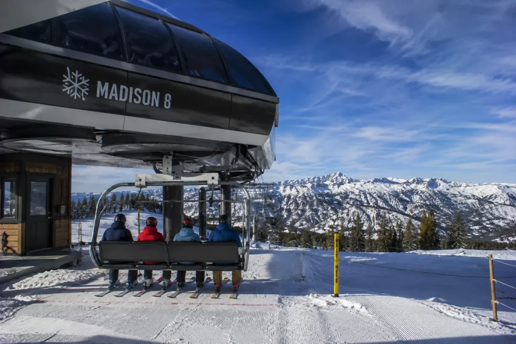 The new high-speed quad chairlift at Red Lodge Mountain loading skiers under a clear blue winter sky with snow-covered peaks in the background