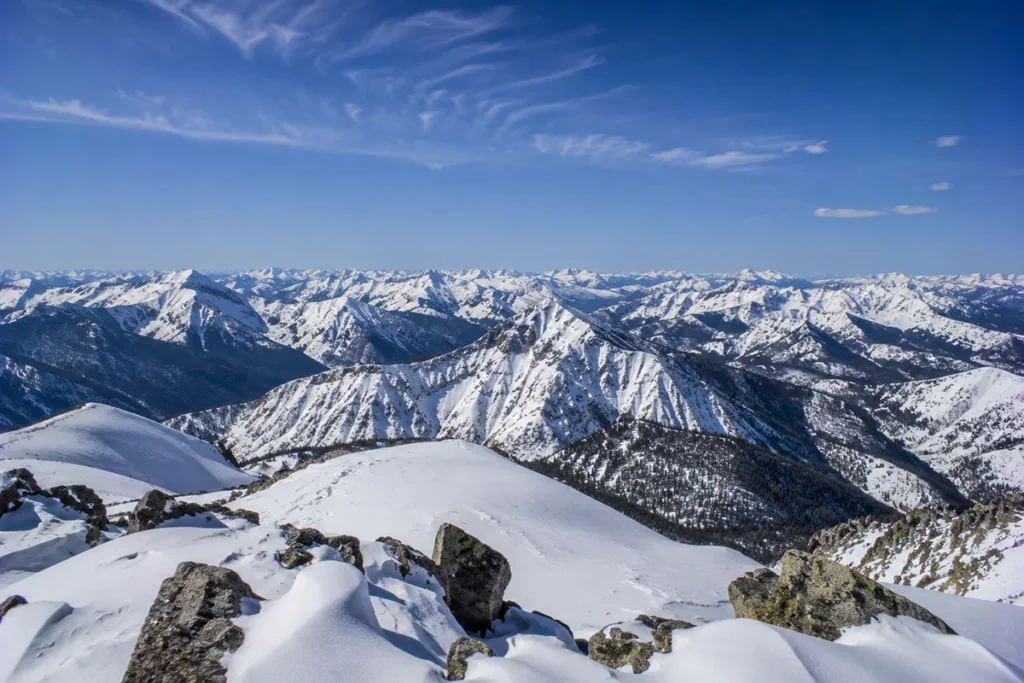 View from the summit of Saddle Mountain at Lost Trail Powder Mountain looking out across multiple mountain ranges of the Northern Rockies stretching to the horizon"