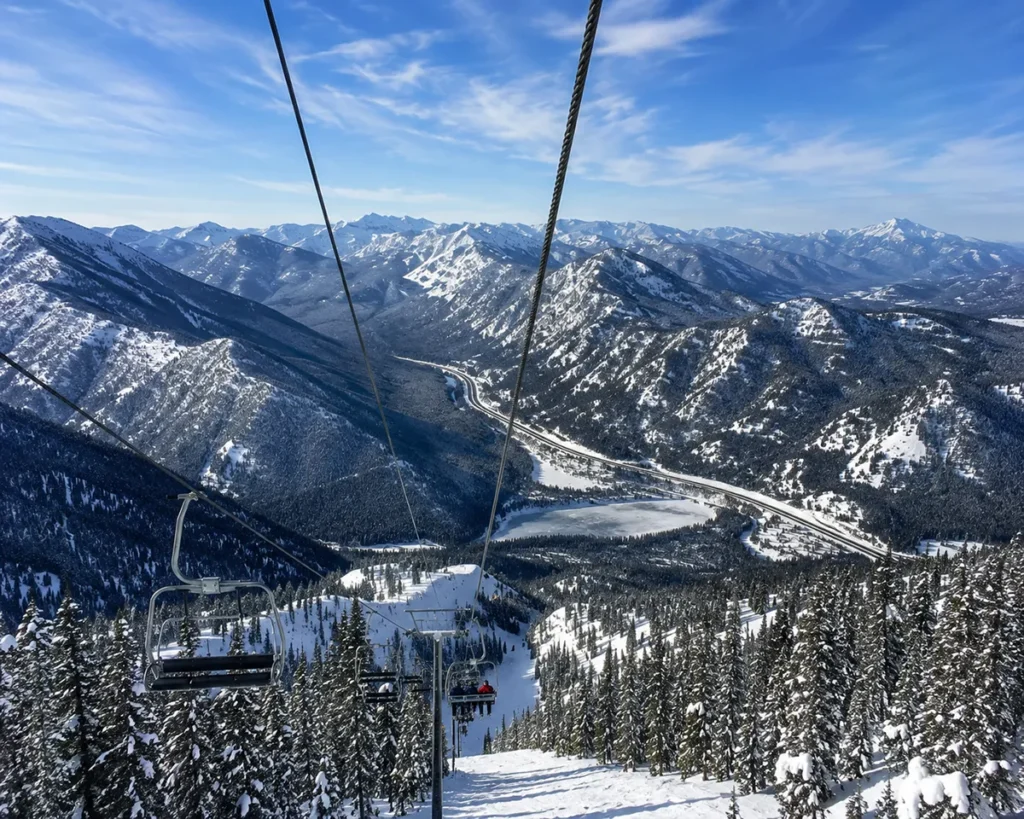 View from a lift at Lookout Pass looking out across the Bitterroot Mountains with the I-90 corridor visible far below as a thin ribbon between snow-covered ridges