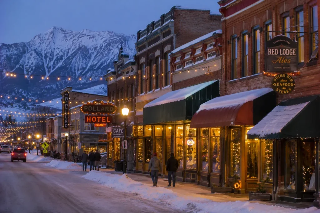 Historic main street Broadway Avenue in downtown Red Lodge Montana on a winter evening with snow on the historic Victorian-era storefronts and warm lights spilling out of restaurants and bars