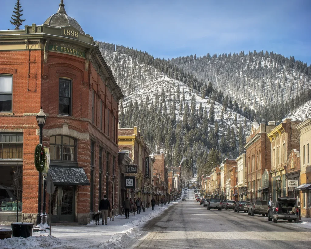 Historic main street in Wallace Idaho with snow on the preserved 1890s-era mining town buildings and the I-90 viaduct visible above