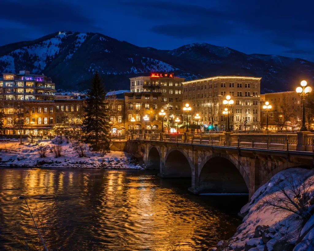 Downtown Missoula Montana with the Higgins Avenue bridge over the Clark Fork River illuminated at night and snow on the riverbanks