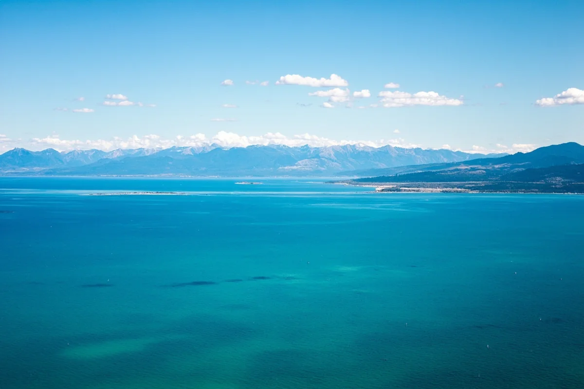 Aerial view of Flathead Lake with Mission Mountains in background, crystal clear turquoise water