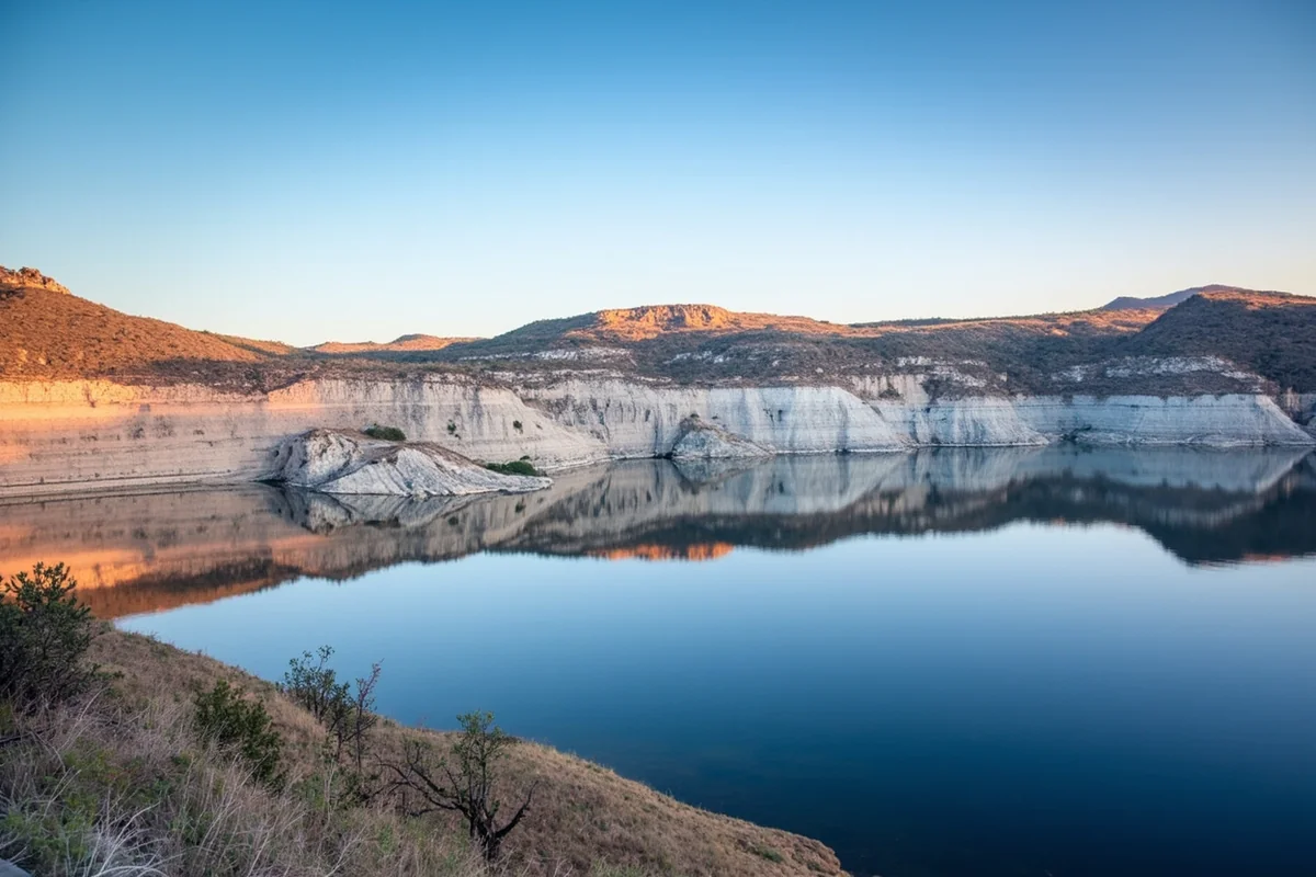 Lake Elwell (Tiber Reservoir) with white clay bluffs reflecting in calm morning water