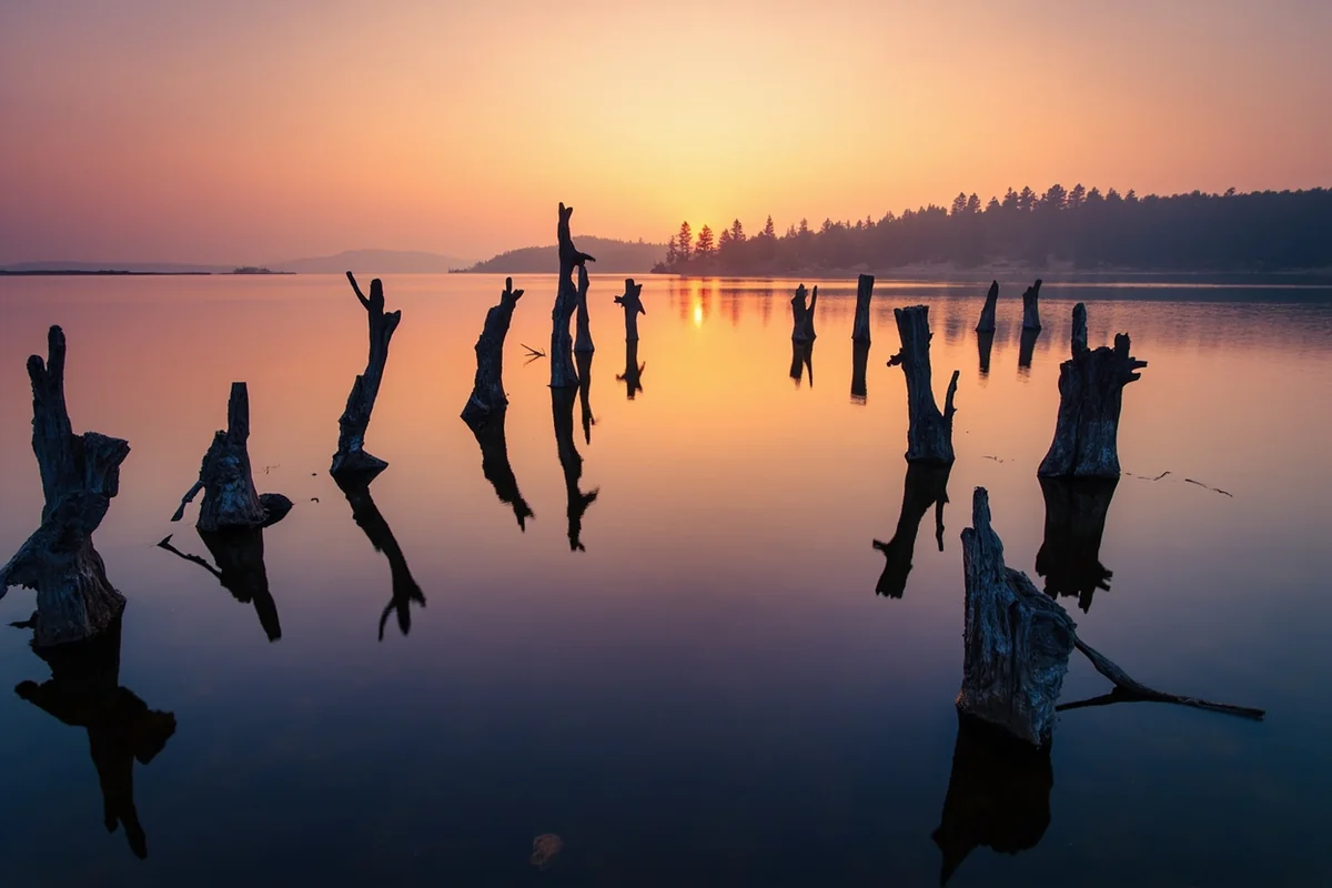 Quake Lake at sunrise showing tree trunks still protruding from the water surface, a haunting reminder of the 1959 earthquake