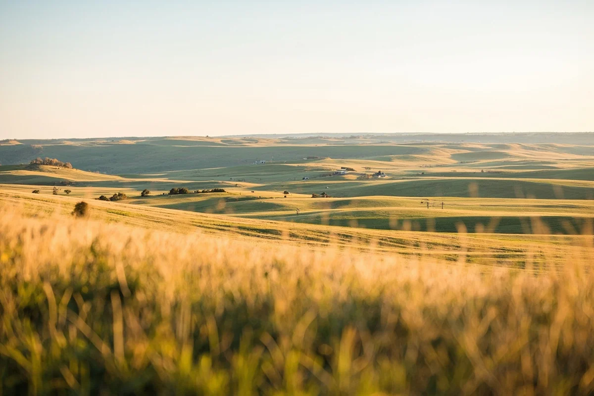 View from Highway 39 south of Forsyth, rolling prairie with a ranch in the middle distance