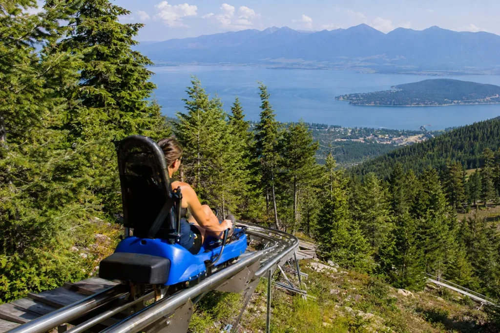Flathead Lake Alpine Coaster in Lakeside Montana showing the coaster track descending through trees with Flathead Lake visible below