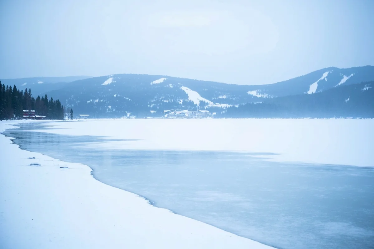 Frozen Whitefish Lake in winter with snow-covered mountains in the background